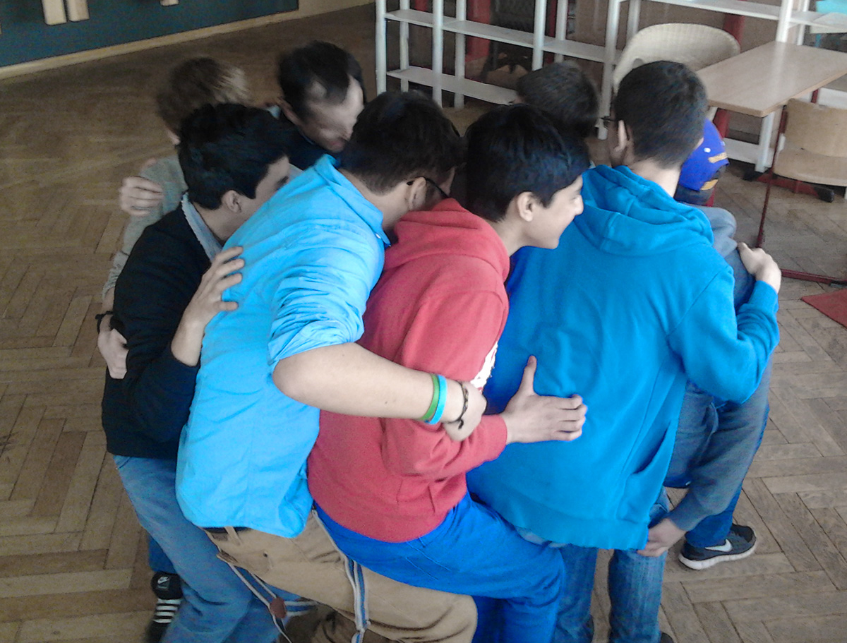 Männliche Jugendliche spielen lachend das Vertrauensspiel Kreissitzen